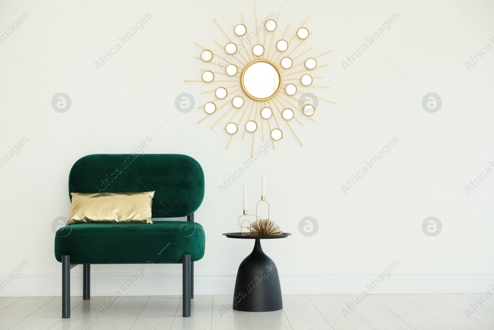 Stylish armchair with cushion and other decor near white wall in room. Interior design Photo of Stylish armchair with cushion and other decor near white wall in room. Interior design