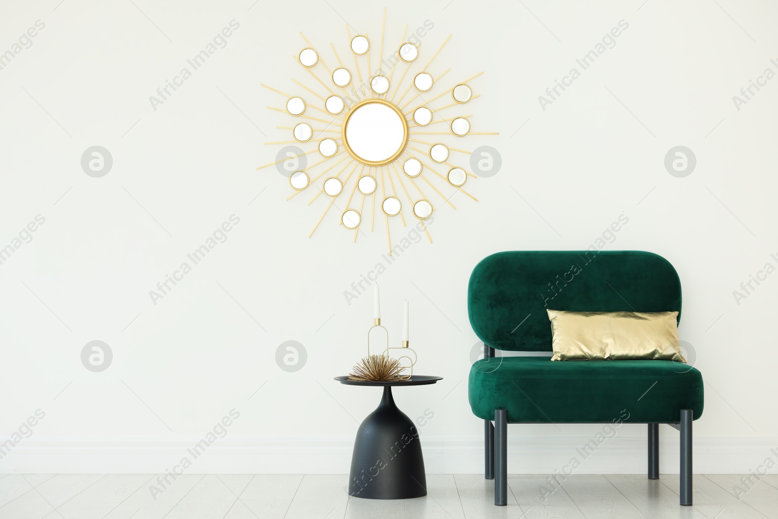 Photo of Stylish armchair with cushion and other decor near white wall in room. Interior design