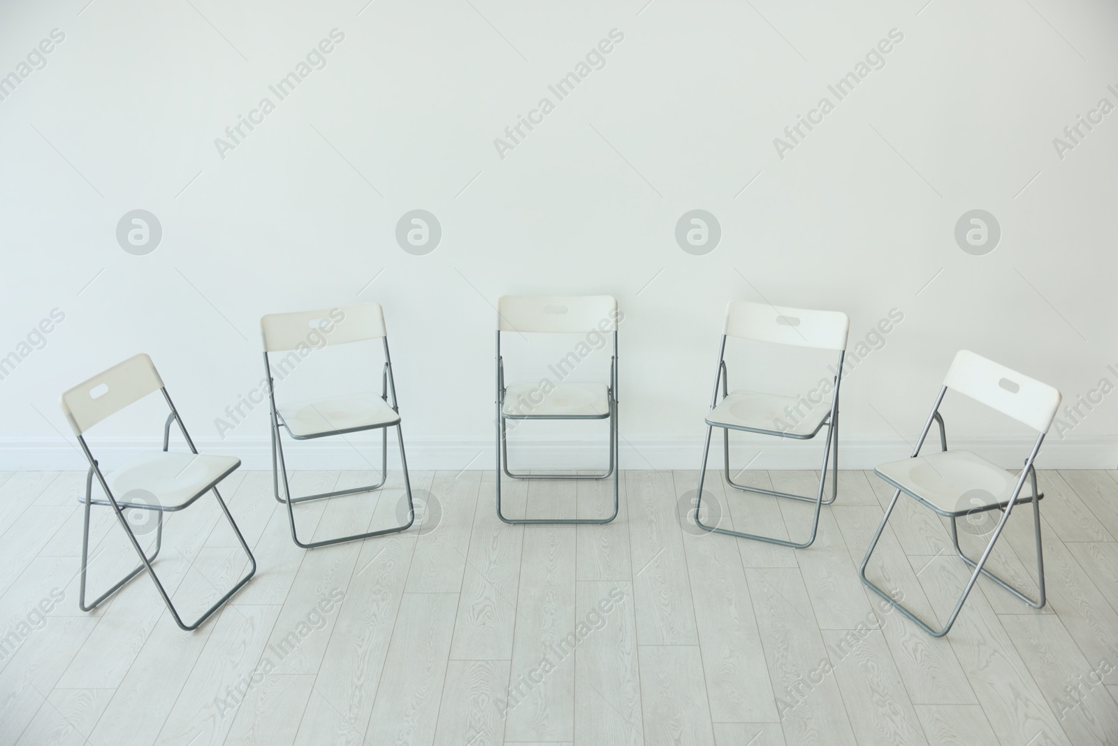 Photo of Many chairs near white wall in room