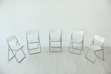 Photo of Many chairs near white wall in room