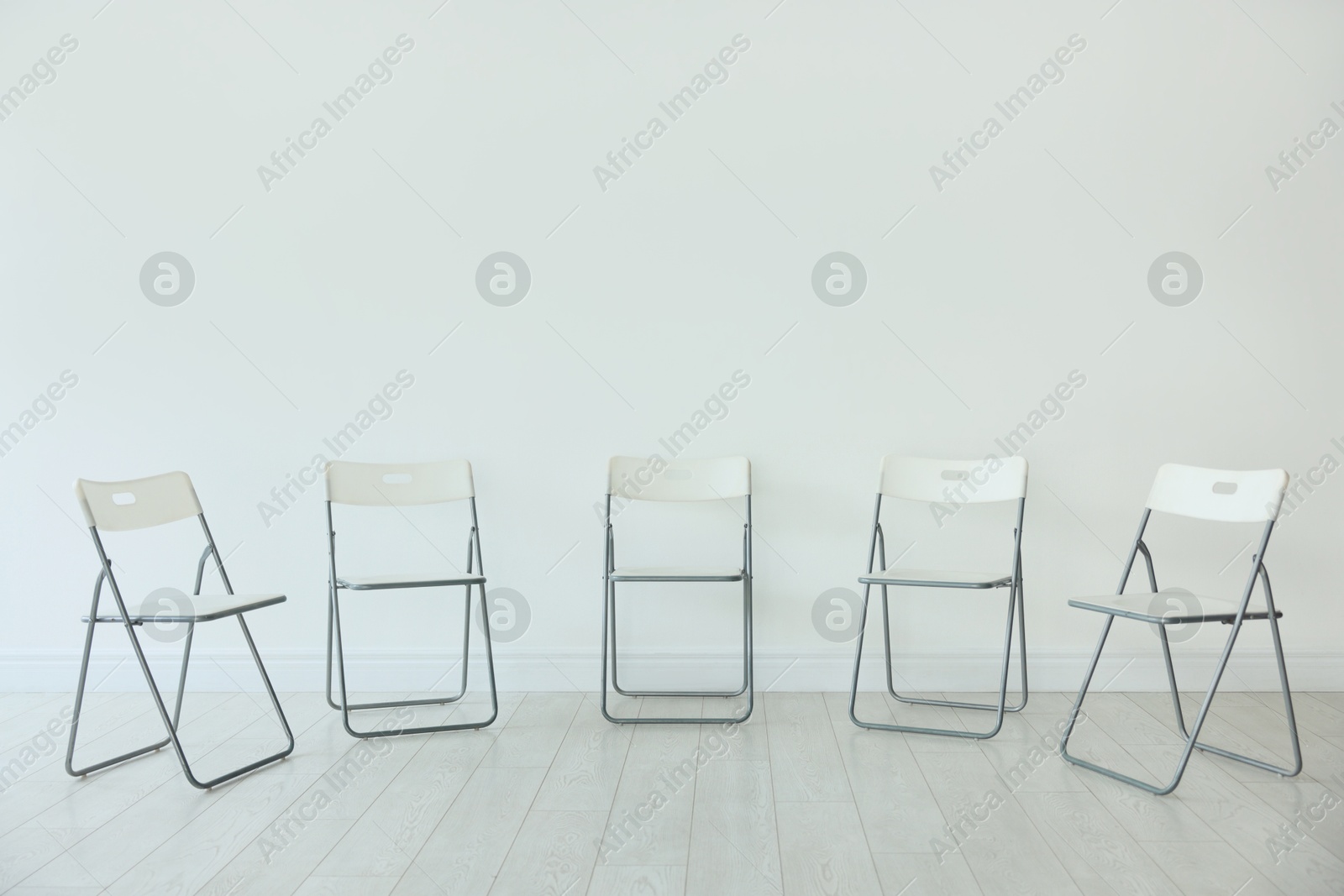 Many chairs near white wall in room Photo of Many chairs near white wall in room