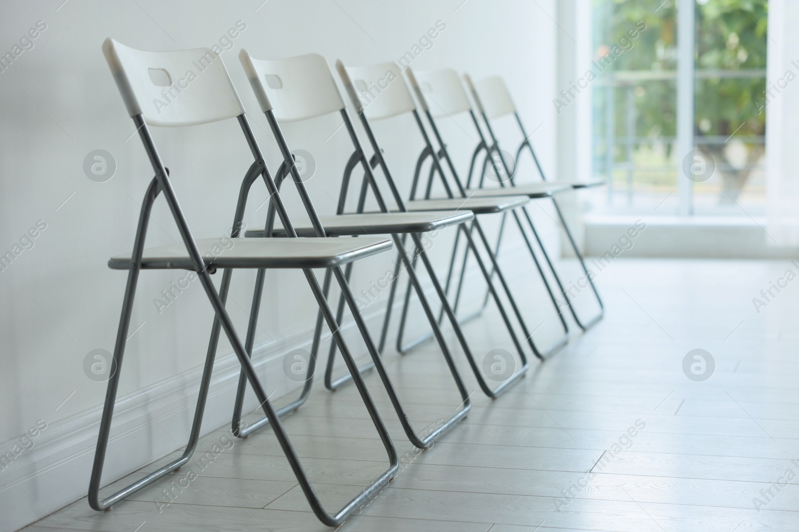Photo of Many stylish chairs near white wall in room