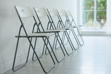 Photo of Many stylish chairs near white wall in room