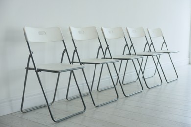 Photo of Many stylish chairs near white wall in room