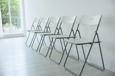 Photo of Many stylish chairs near white wall in room