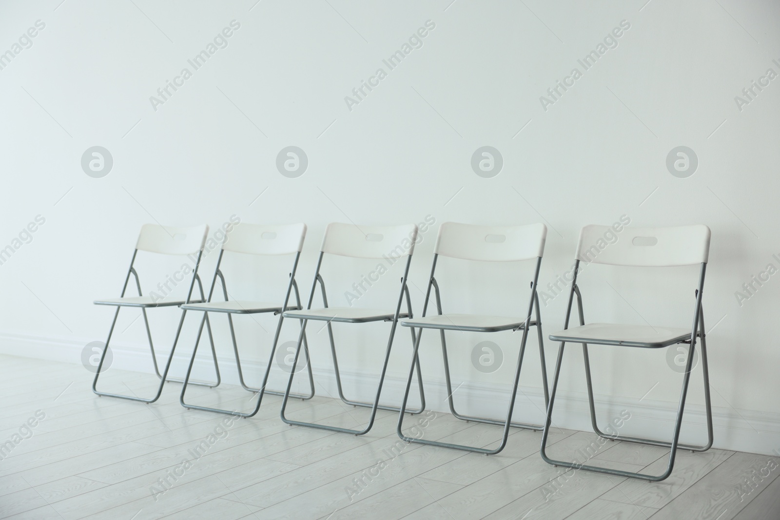 Photo of Many chairs near white wall in room