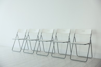 Photo of Many chairs near white wall in room