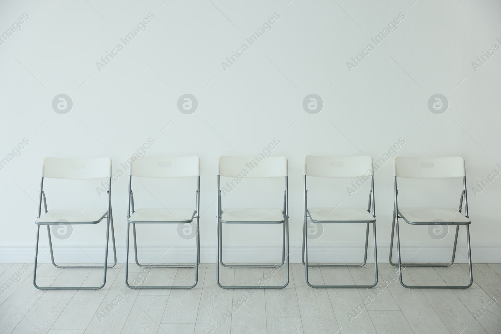 Photo of Many chairs near white wall in room