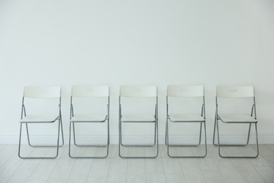 Photo of Many chairs near white wall in room
