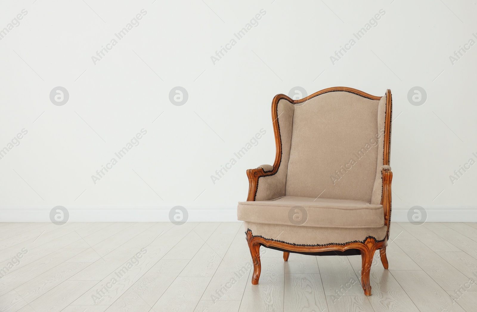 Stylish armchair near white wall indoors, space for text Photo of Stylish armchair near white wall indoors, space for text