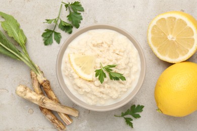 Photo of Tasty horseradish sauce with parsley, lemon slice and roots on light table, flat lay