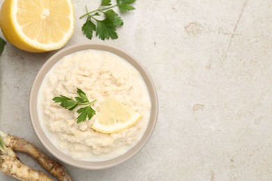 Photo of Tasty horseradish sauce with parsley, lemon slice and roots on light table, flat lay. Space for text