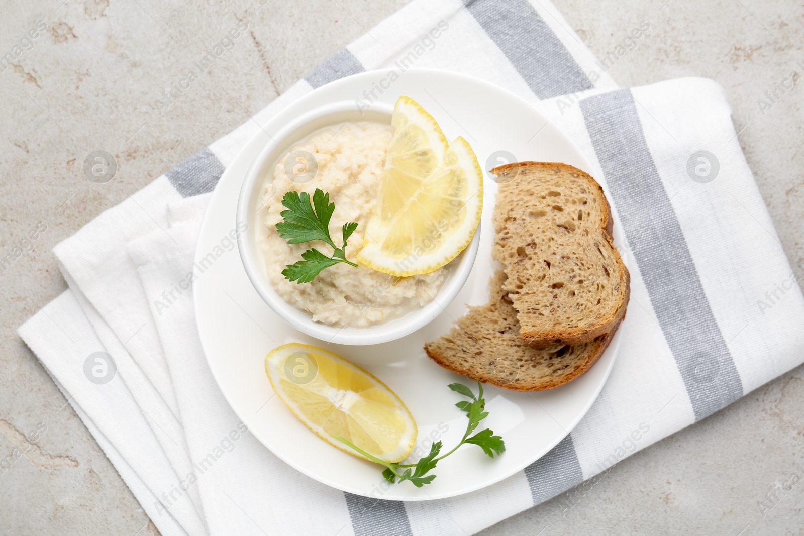 Photo of Tasty horseradish sauce with parsley and lemon slices served on light table, top view