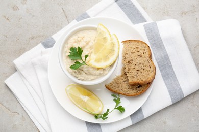 Photo of Tasty horseradish sauce with parsley and lemon slices served on light table, top view