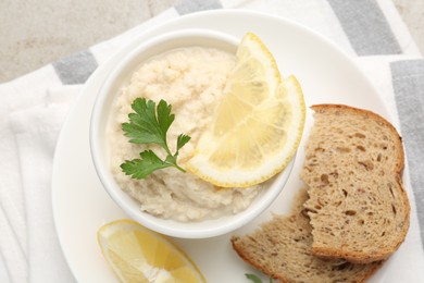 Photo of Tasty horseradish sauce with parsley and lemon slices served on light table, top view