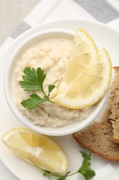 Photo of Tasty horseradish sauce with parsley and lemon slices served on light table, top view