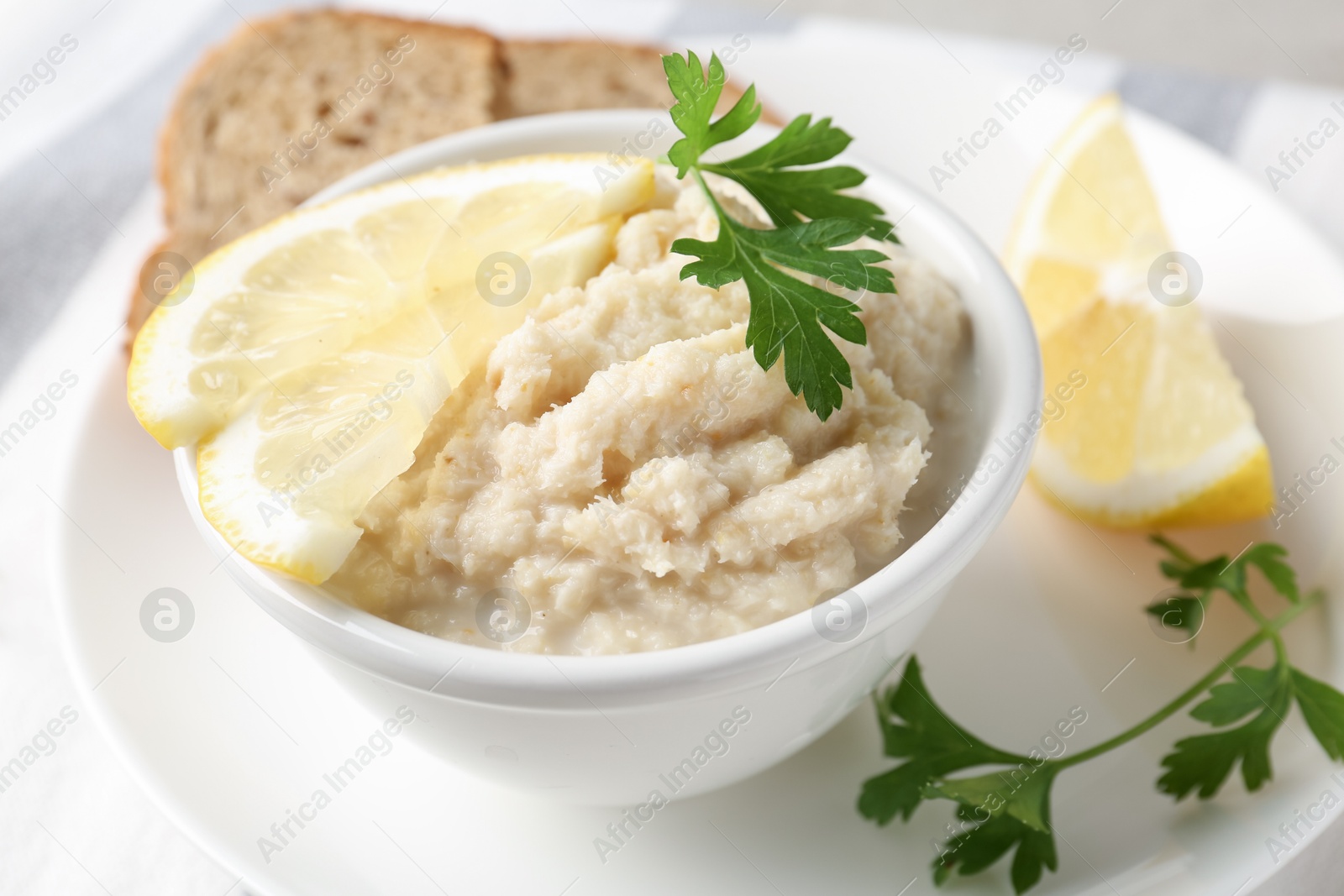 Photo of Tasty horseradish sauce with parsley and lemon slices served on light table, closeup