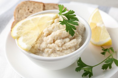 Photo of Tasty horseradish sauce with parsley and lemon slices served on light table, closeup
