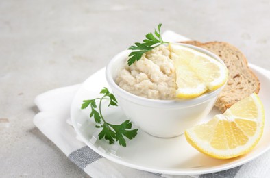 Photo of Tasty horseradish sauce with parsley and lemon slices served on light table, closeup