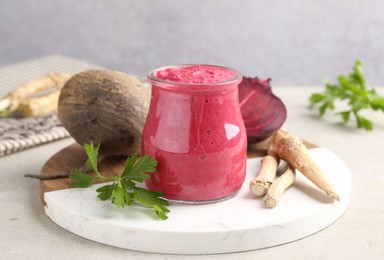 Photo of Tasty horseradish sauce with beetroot, parsley, roots and vegetables on light table, closeup