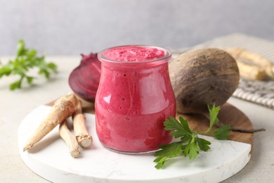 Photo of Tasty horseradish sauce with beetroot, parsley, roots and vegetables on light table, closeup