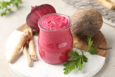 Photo of Tasty horseradish sauce with beetroot, parsley, roots and vegetables on light table, closeup