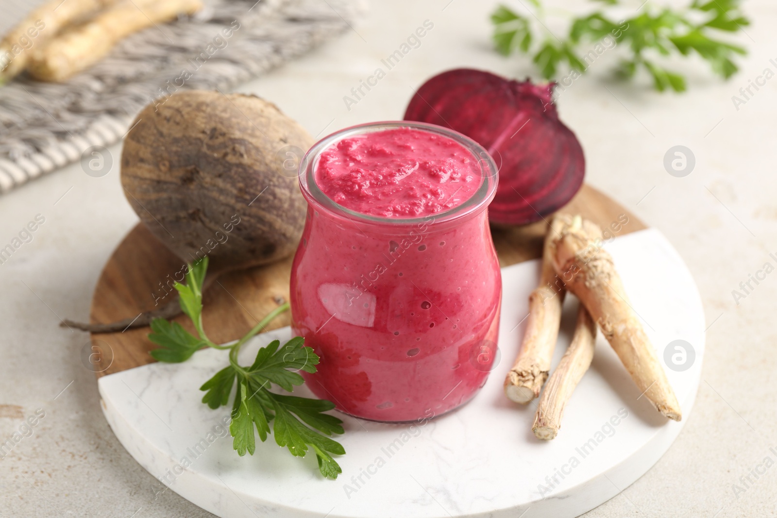 Photo of Tasty horseradish sauce with beetroot, parsley, roots and vegetables on light table, closeup