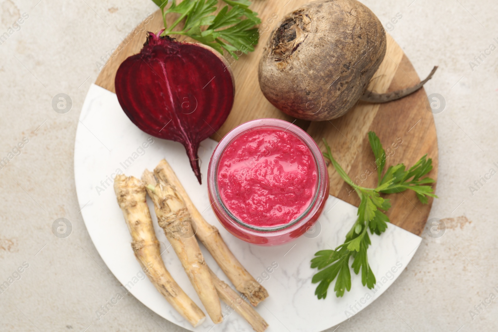 Photo of Tasty horseradish sauce with beetroot, parsley, roots and vegetables on light table, top view