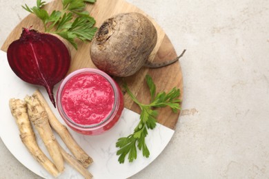 Photo of Tasty horseradish sauce with beetroot, parsley, roots and vegetables on light table, top view. Space for text