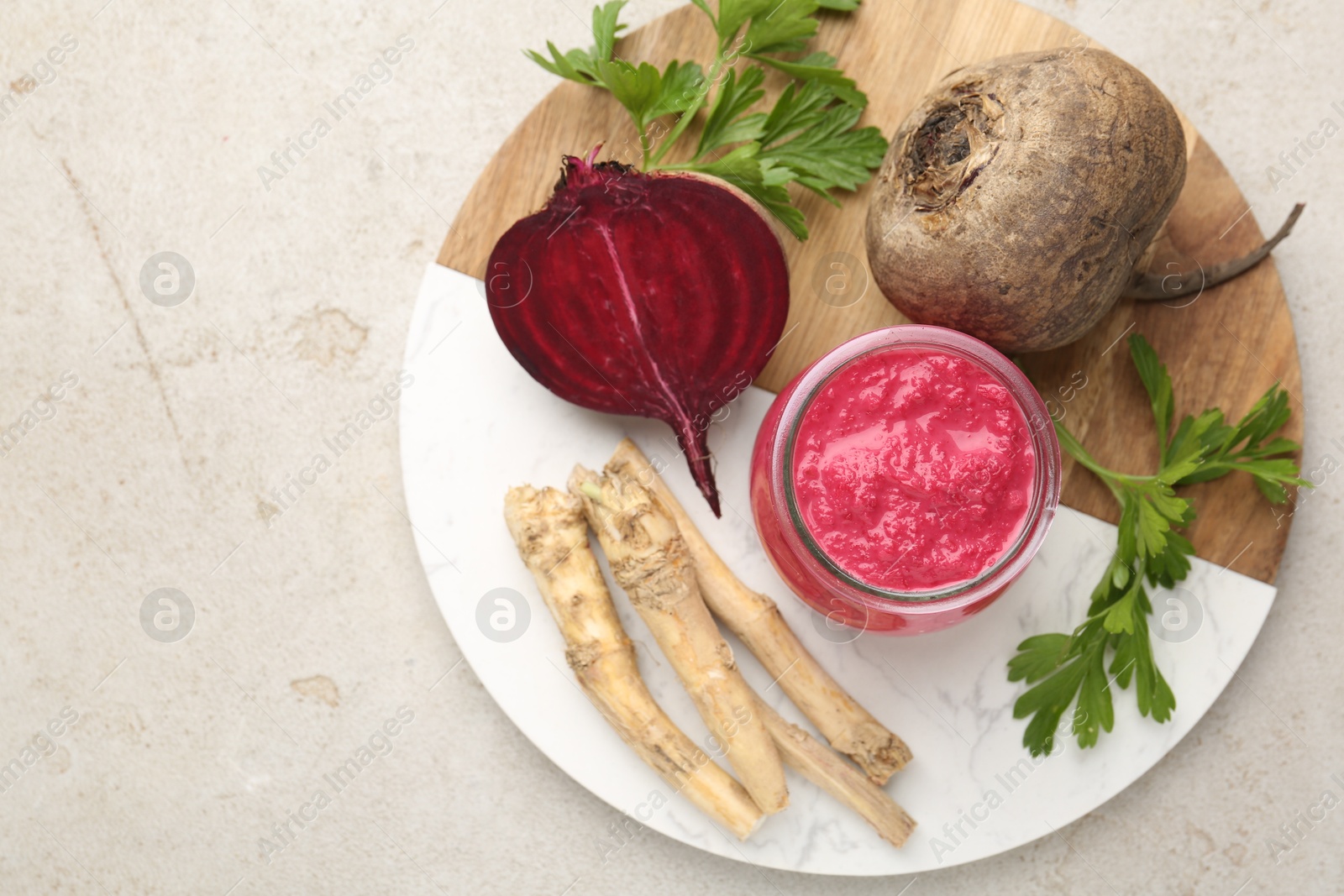 Photo of Tasty horseradish sauce with beetroot, parsley, roots and vegetables on light table, top view