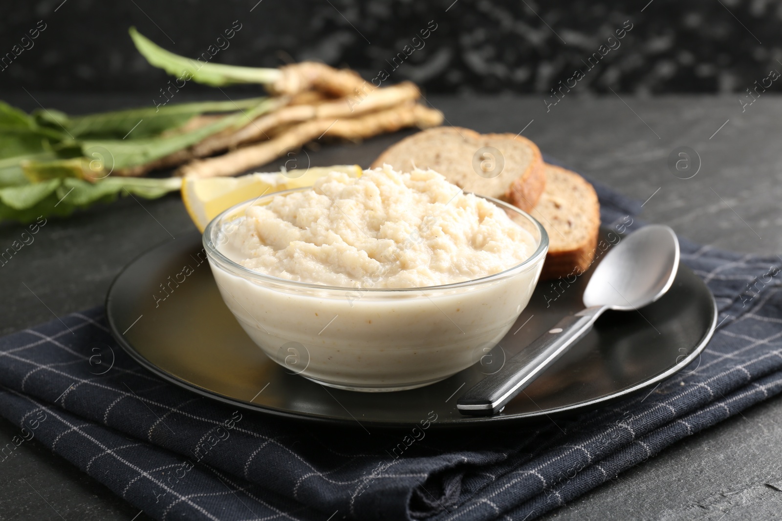 Photo of Tasty horseradish sauce served on black table, closeup