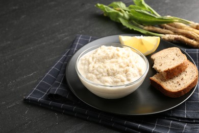Photo of Tasty horseradish sauce served on black table, closeup. Space for text