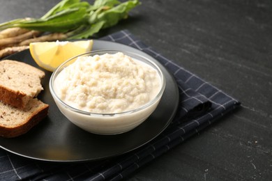 Photo of Tasty horseradish sauce served on black table, closeup. Space for text