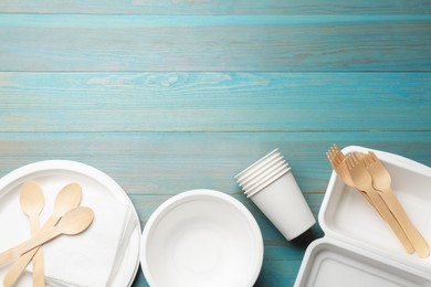 Photo of Set of disposable tableware on light blue wooden table, flat lay. Space for text
