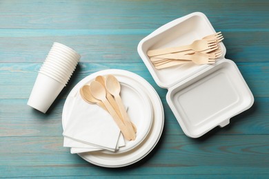 Photo of Set of disposable tableware and napkins on light blue wooden table, flat lay