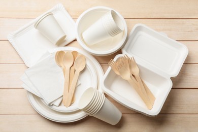 Photo of Set of disposable tableware and napkins on wooden table, flat lay