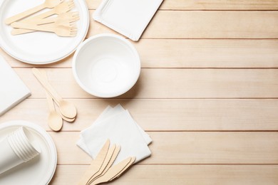 Photo of Set of disposable tableware and napkins on wooden table, flat lay. Space for text