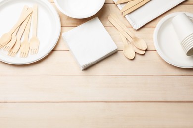 Photo of Set of disposable tableware and napkins on wooden table, flat lay. Space for text