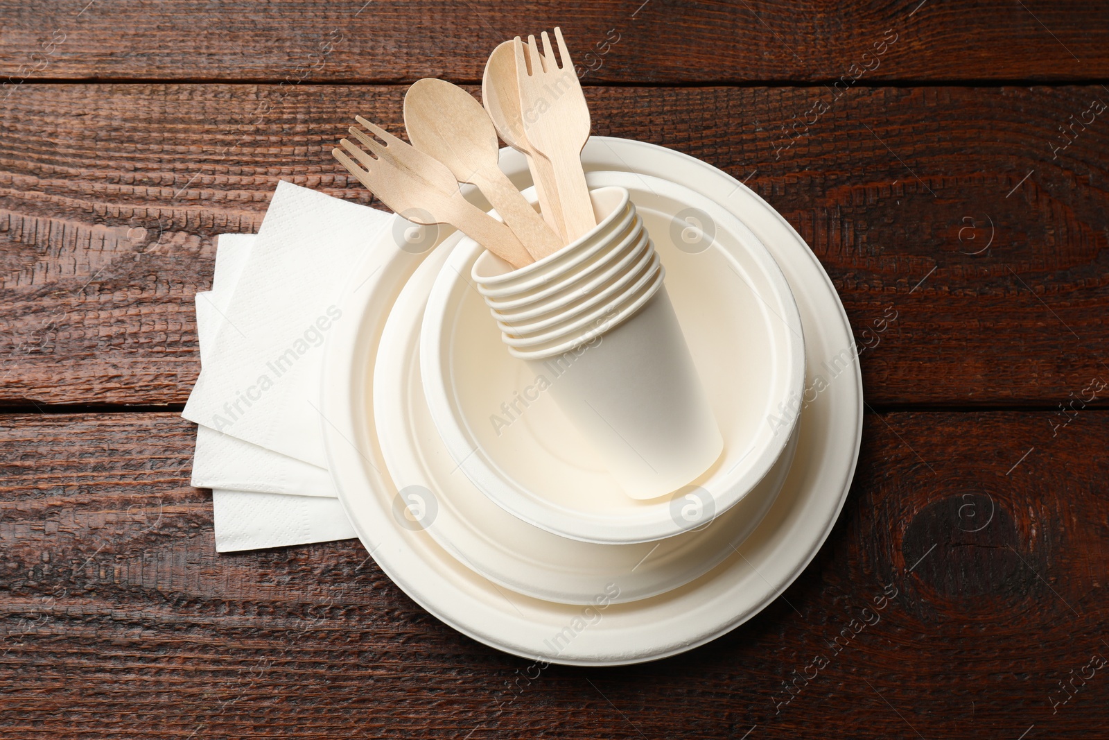 Photo of Set of disposable tableware and napkins on wooden table, top view