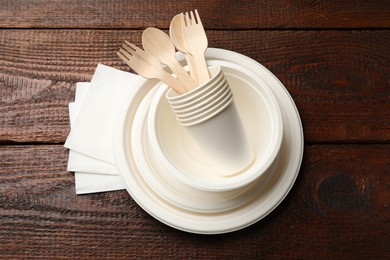 Photo of Set of disposable tableware and napkins on wooden table, top view