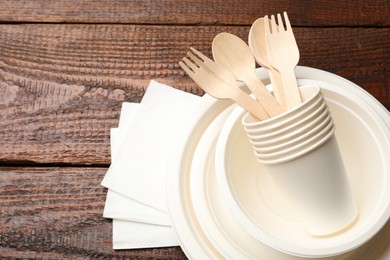 Photo of Set of disposable tableware and napkins on wooden table, top view. Space for text
