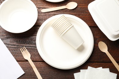 Photo of Set of disposable tableware and napkins on wooden table, flat lay