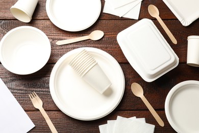 Photo of Set of disposable tableware and napkins on wooden table, flat lay