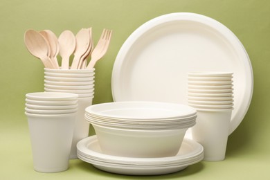 Photo of Set of disposable tableware on green background