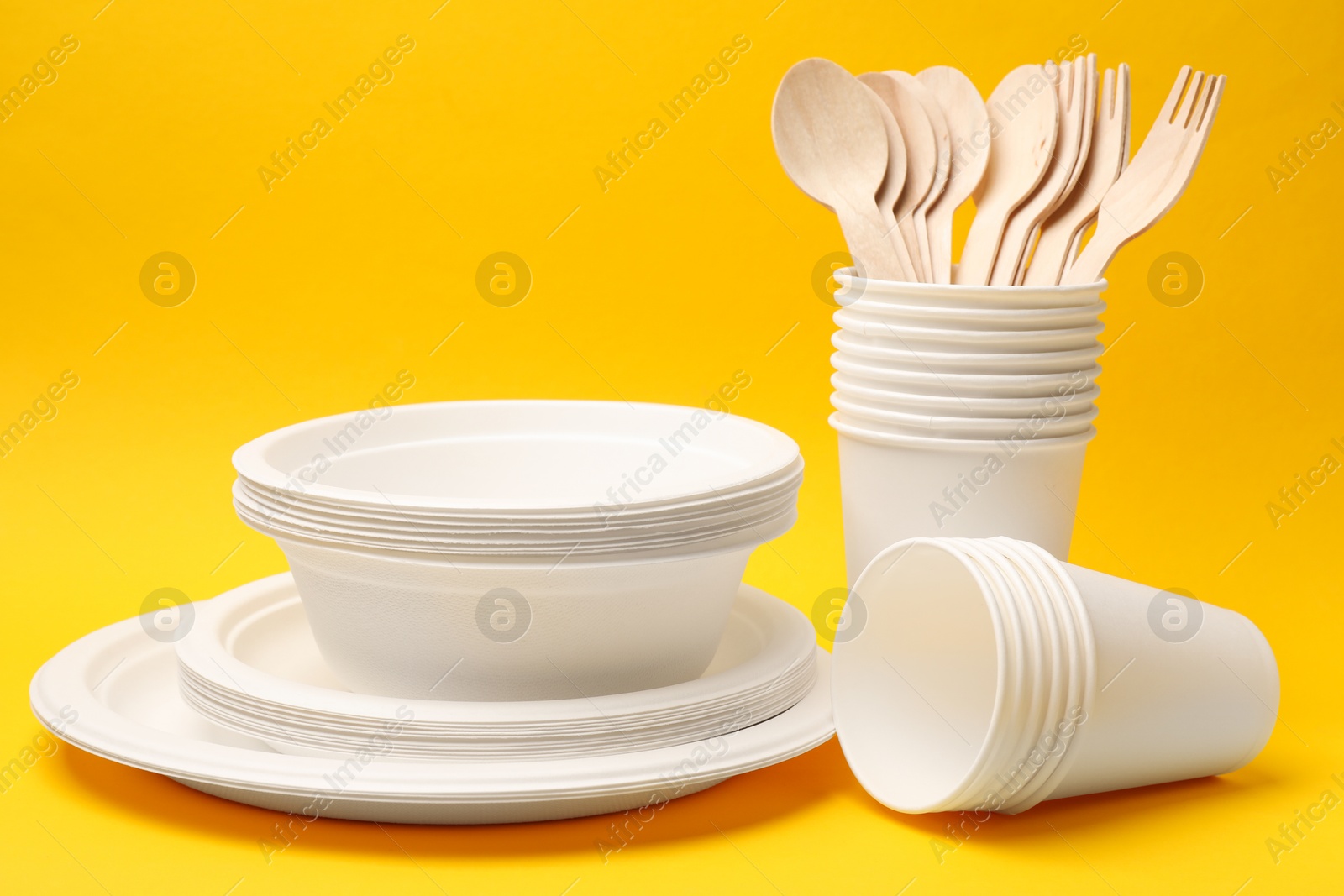 Photo of Set of disposable tableware on yellow background