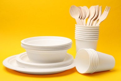 Photo of Set of disposable tableware on yellow background