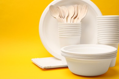 Photo of Set of disposable tableware on yellow background. Space for text
