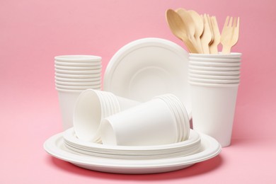 Photo of Set of disposable tableware on pink background