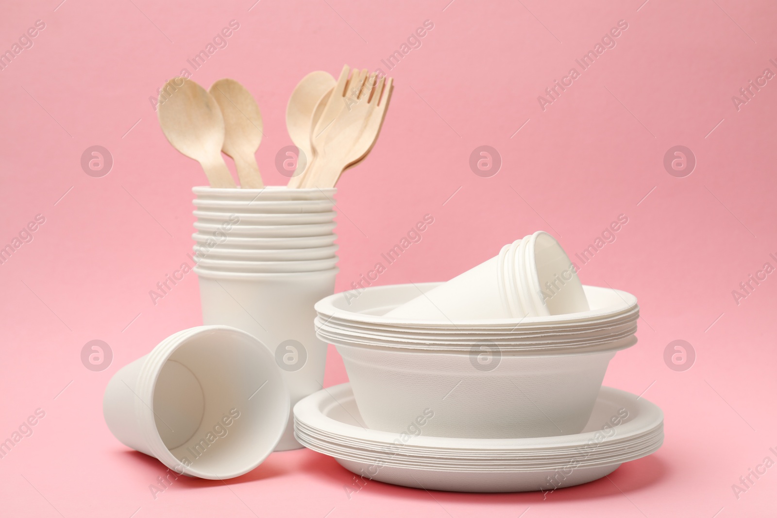 Photo of Set of disposable tableware on pink background