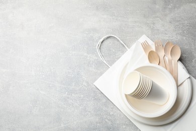 Photo of Set of disposable tableware, paper bag and napkins on grey table, top view. Space for text